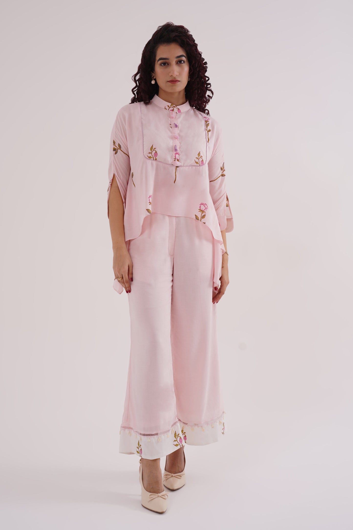 Woman wearing a light pink traditional outfit with floral patterns on a white background